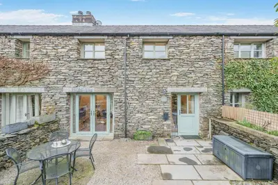 a stone house with a patio and a table and chairs at 2 Bed in Ulverston oc-sz013 in Haverthwaite
