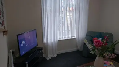 a living room with a tv and a chair and a window at Blackpool Central Beach Apartments in Blackpool