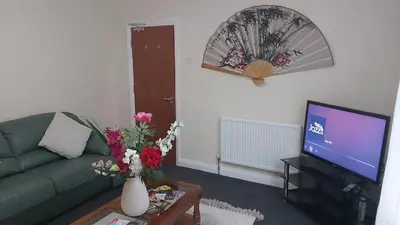 a living room with a green couch and a tv at Blackpool Central Beach Apartments in Blackpool