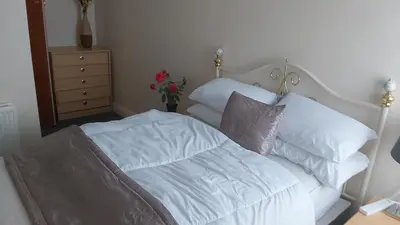 a white bed with white pillows and a vase with flowers at Blackpool Central Beach Apartments in Blackpool
