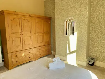 a bedroom with a large bed and a wooden dresser at Cosy 4 bedroom house in Marshside