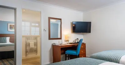 a hotel room with a desk and a bed and a mirror at Last Drop Village Hotel & Spa in Bolton