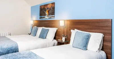a hotel room with two beds and a painting on the wall at Last Drop Village Hotel & Spa in Bolton