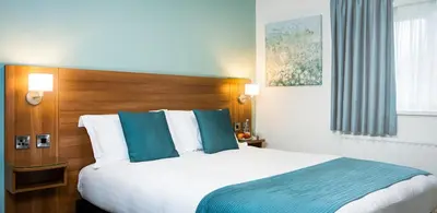 a hotel room with a large bed with blue pillows at Last Drop Village Hotel & Spa in Bolton