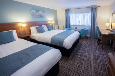 a hotel room with two beds and a desk at Last Drop Village Hotel & Spa in Bolton