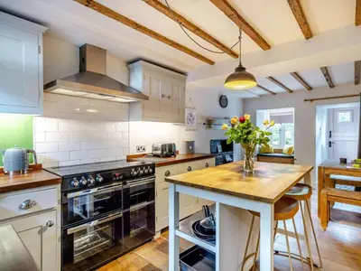 a kitchen with white cabinets and a wooden counter top at 3 Bed in Ulverston oc-87960 in Greenodd