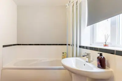 a white bathroom with a sink and a bath tub at Spacious 3-bed Home - Nature Reserve Retreat in Ince-in-Makerfield