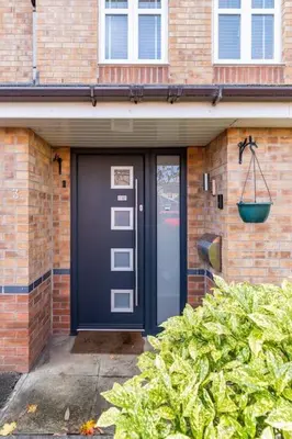 a blue door on a brick house with a plant at Spacious 3-bed Home - Nature Reserve Retreat in Ince-in-Makerfield