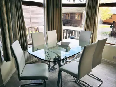 a room with chairs and a glass table and a window at Luxury 3 bedroom lodge with free in lodge wifi in Carnforth