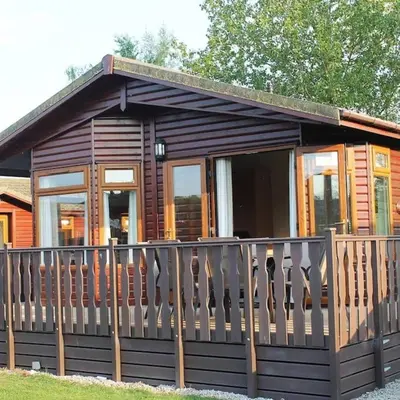 a small wooden cabin with a wooden fence at Luxury 3 bedroom lodge with free in lodge wifi in Carnforth