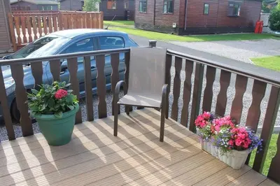 a wooden deck with a chair and two potted plants at Luxury 3 bedroom lodge with free in lodge wifi in Carnforth