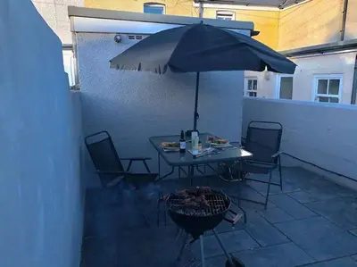 a table and chairs with an umbrella on a patio at Outskirts of Ulverston, entire Cottage - sleeps 4 in Ulverston