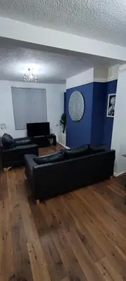 a living room with two black couches and a blue wall at Your Happy Place-2 Bedroom House in Liverpool