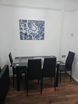 a dining room table with chairs and a painting on the wall at Your Happy Place-2 Bedroom House in Liverpool