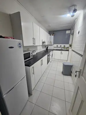 a kitchen with white cabinets and a refrigerator at Your Happy Place-2 Bedroom House in Liverpool
