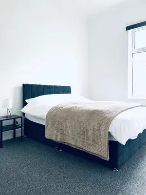 a bedroom with a large bed with white sheets and a window at Valley Road, Anfield LFC in Liverpool