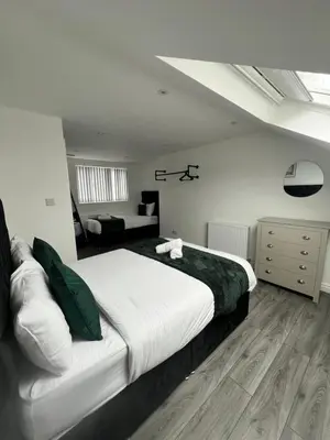 a bedroom with a large bed and a living room at Central Location Liverpool, Modern Home, 4 BR, Sleeps 9, Free Parking in Liverpool