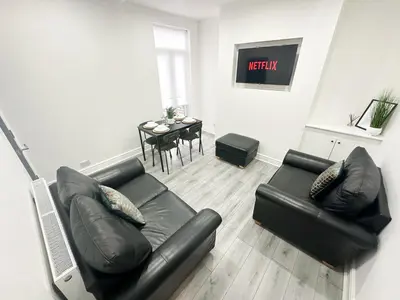 a living room with a black leather couch and a table at Central Location Liverpool, Modern Home, 4 BR, Sleeps 9, Free Parking in Liverpool
