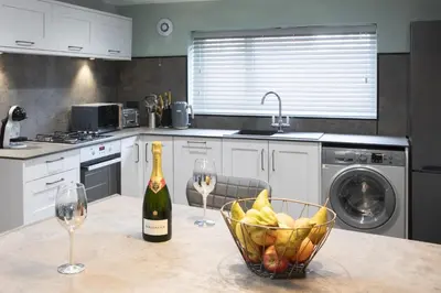 a kitchen with a bowl of fruit and a bottle of wine at Botanic Cottages in Southport