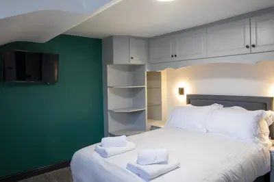 a bedroom with a white bed with towels on it at Botanic Cottages in Southport