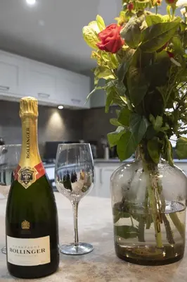 a bottle of wine and a vase with a glass at Botanic Cottages in Southport