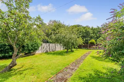 a garden with trees and a fence at Botanic Cottages in Southport