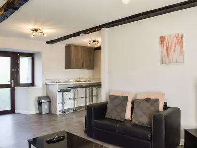a living room with a couch and a kitchen at Beck Cottage in Millom