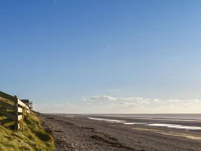 a beach with a fence and the ocean at Beck Cottage in Millom