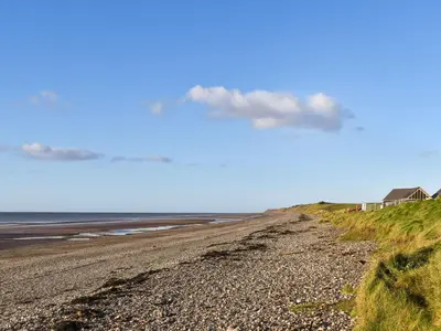 a rocky beach with a house and the ocean at Beck Cottage in Millom