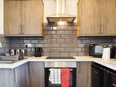 a kitchen with wooden cabinets and a stove top oven at Beck Cottage in Millom