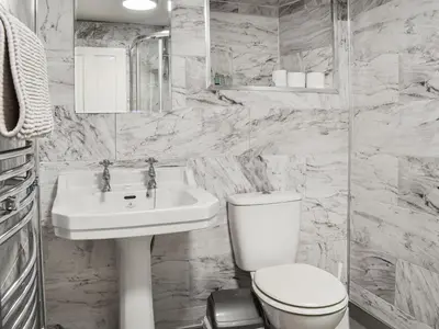 a white bathroom with a toilet and a sink at Beck Cottage in Millom