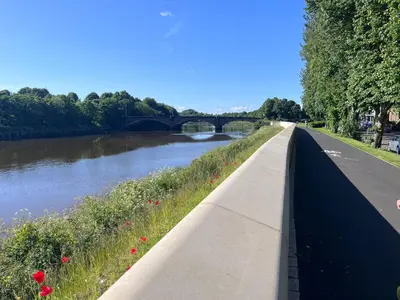 a path next to a river with a bridge at Riverside by Teil in Preston