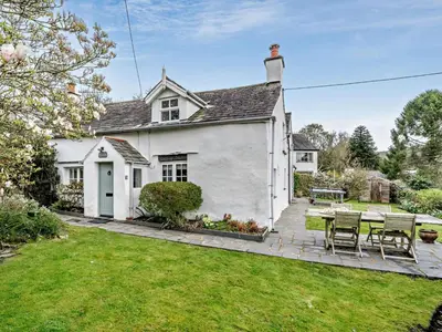 a white house with a table and chairs in the yard at 3 Bed in Ulverston oc-91779 in Haverthwaite