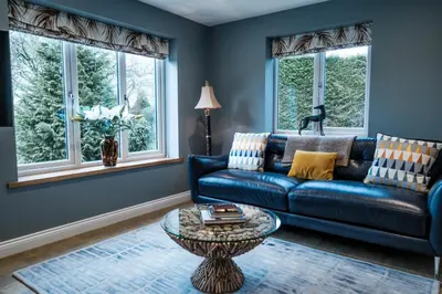 a blue living room with a blue couch and windows at Bramley Brook Cottage 5* Luxury in Whalley