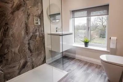 a bathroom with a glass shower and a window at Bramley Brook Cottage 5* Luxury in Whalley