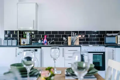 a kitchen with white appliances and a table with wine glasses at Spacious One-Bedroom Apartment in Saint Helens in Saint Helens