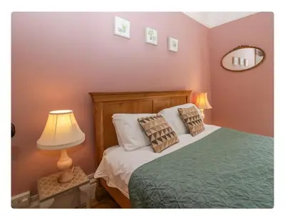 a bedroom with a bed with two pillows and a lamp at Sunnycote in Arnside