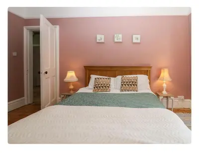 a bedroom with a large white bed with two lamps at Sunnycote in Arnside