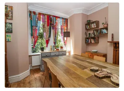a room with a wooden table and a window with curtains at Sunnycote in Arnside