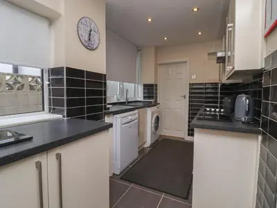 a kitchen with white cabinets and black tiles at 19 Slinger Road in Cleveleys