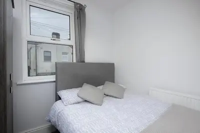 a bed with two pillows sitting next to a window at Beautiful Family Home in Blackpool for you in Blackpool