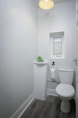a white bathroom with a toilet and a window at Beautiful Family Home in Blackpool for you in Blackpool