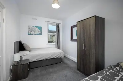 a bedroom with a bed and a wooden cabinet at Beautiful Family Home in Blackpool for you in Blackpool