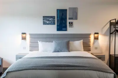 a bedroom with a large bed with two lights on it at The Bolton Stadium Hotel, a member of Radisson Individuals in Bolton