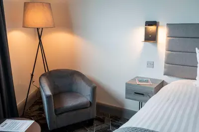 a bedroom with a chair and a bed and a lamp at The Bolton Stadium Hotel, a member of Radisson Individuals in Bolton
