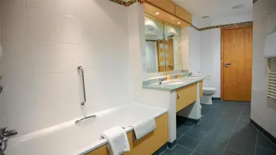 a bathroom with two sinks and a tub and a toilet at The Bolton Stadium Hotel, a member of Radisson Individuals in Bolton