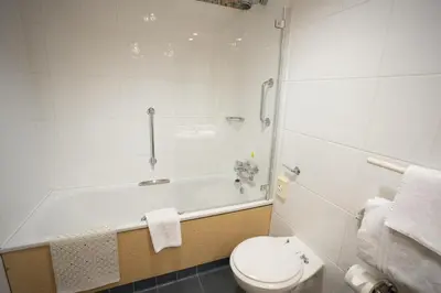 a bathroom with a tub and a toilet and a sink at The Bolton Stadium Hotel, a member of Radisson Individuals in Bolton