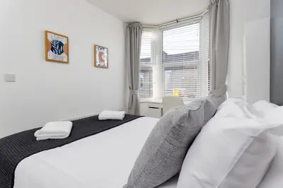 a white bedroom with a bed and a window at St Davids House - Air Host & Stay - 4 Bedrooms - Contractor Friendly in Liverpool