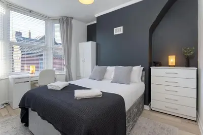a bedroom with a large bed with a blue wall at St Davids House - Air Host & Stay - 4 Bedrooms - Contractor Friendly in Liverpool