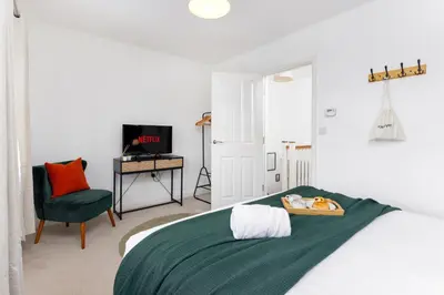 a bedroom with a bed and a chair and a television at Modern 2-Bed Townhouse in Kirkdale in Liverpool